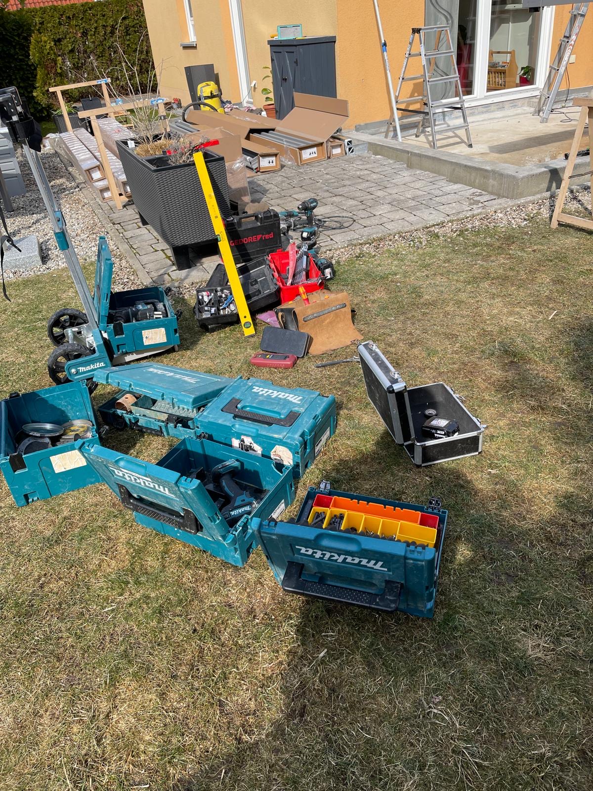 Makita-Werkzeugkoffer und Akku-Geräte ausgebreitet im Garten vor einer Terrasse